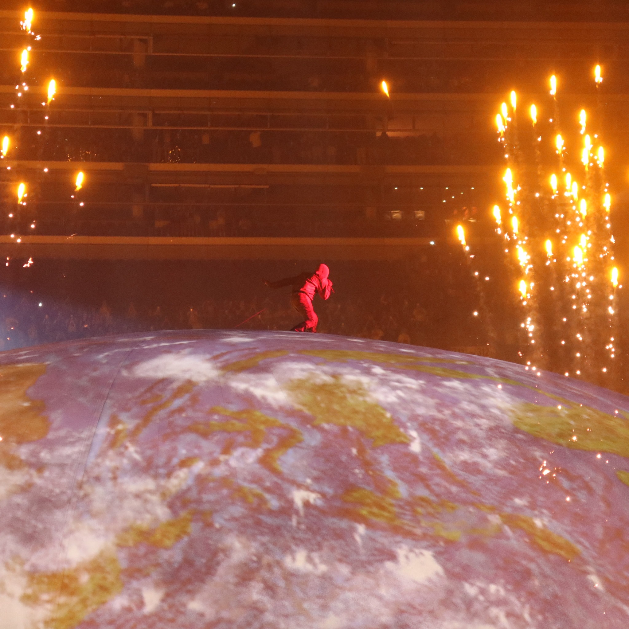 A performer on the dome framed by fireworks