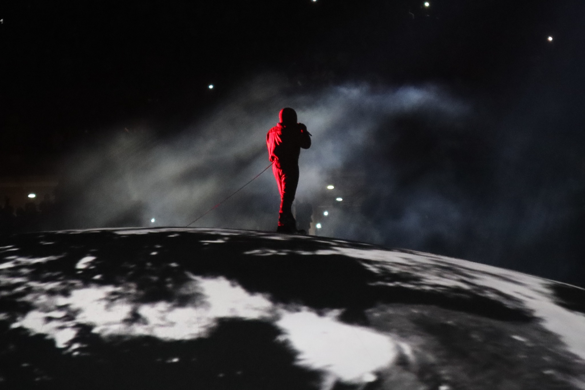 A performer silhouetted in red over the smoky dome