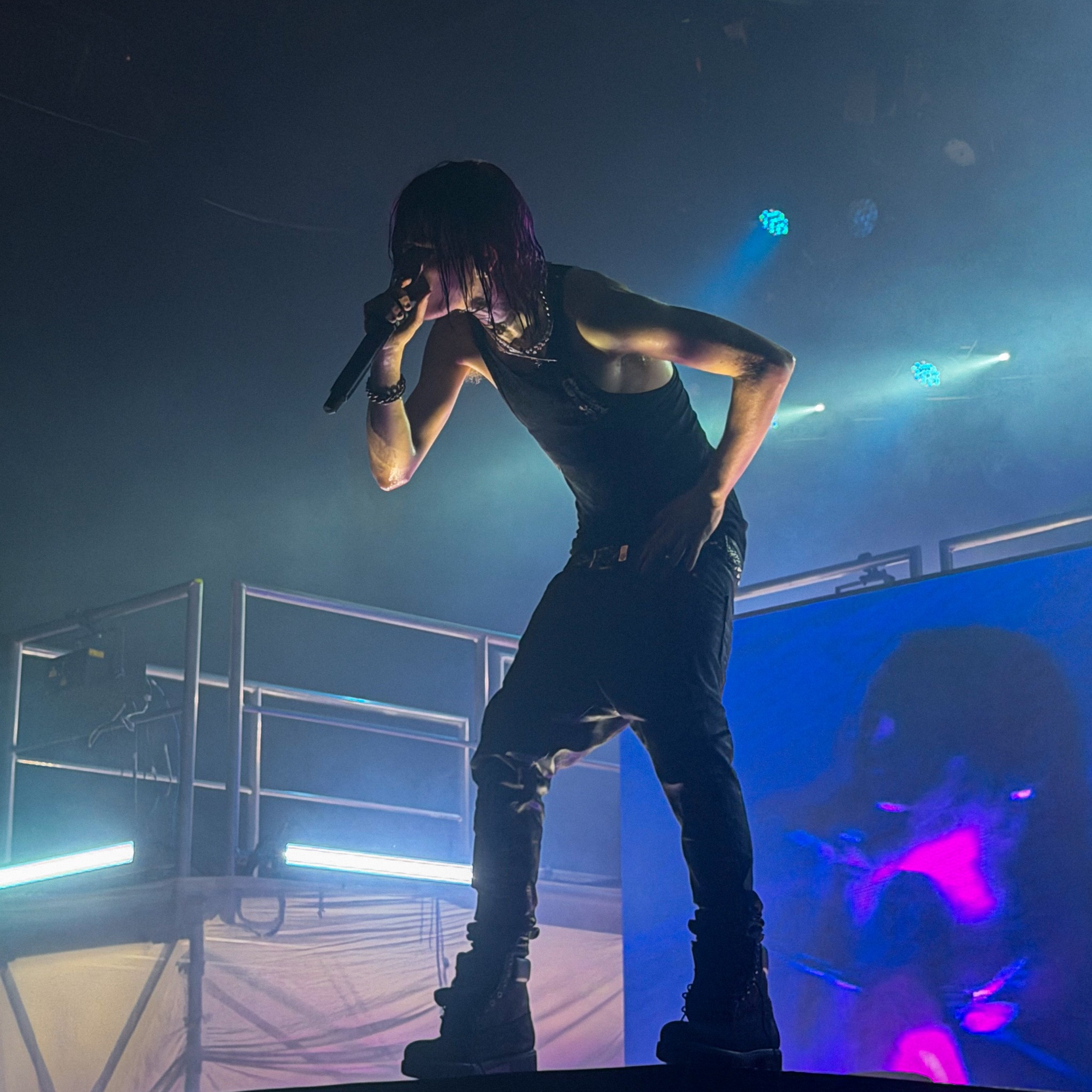 Nettspend leaning toward the crowd under blue stage lights