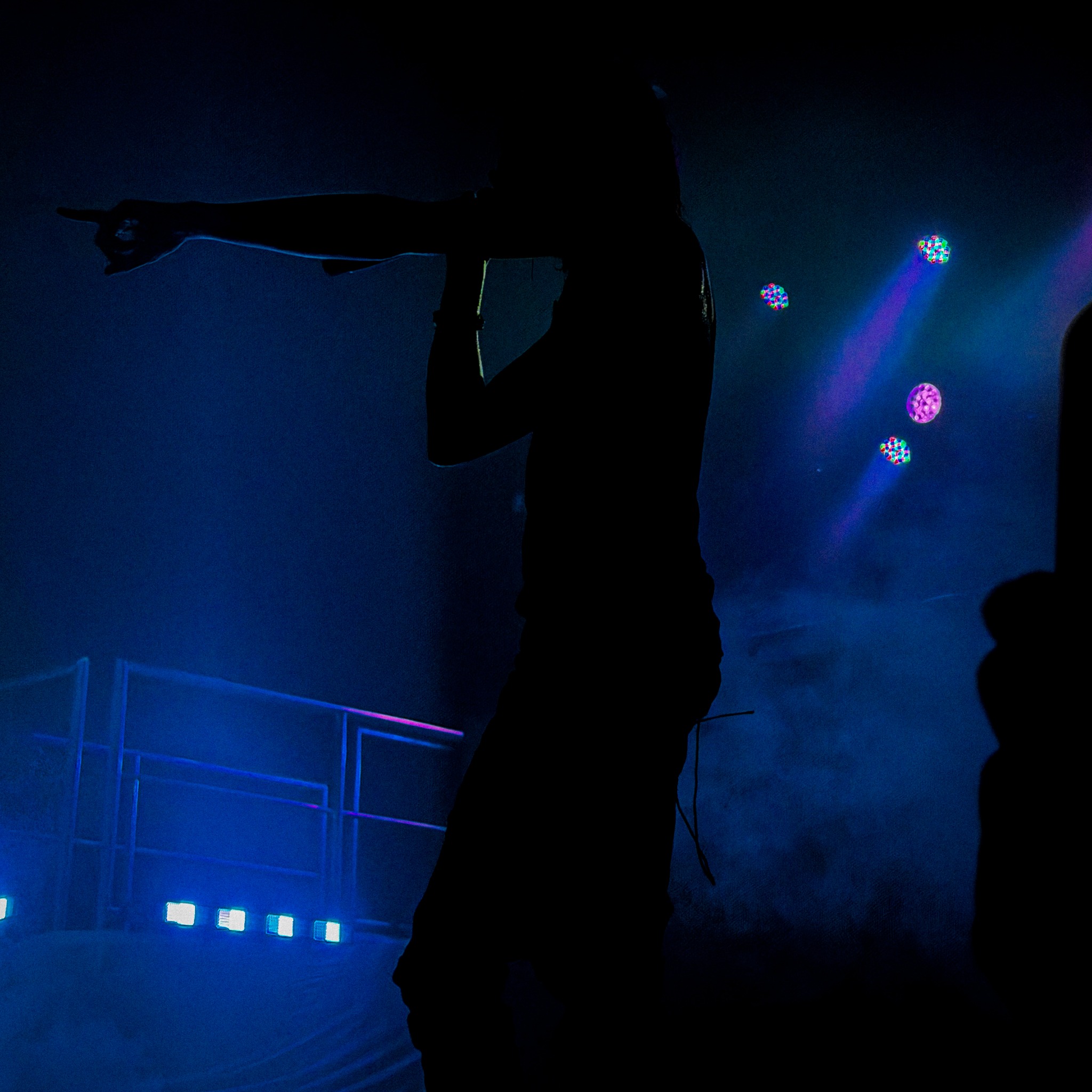 Nettspend silhouetted against deep blue concert lighting