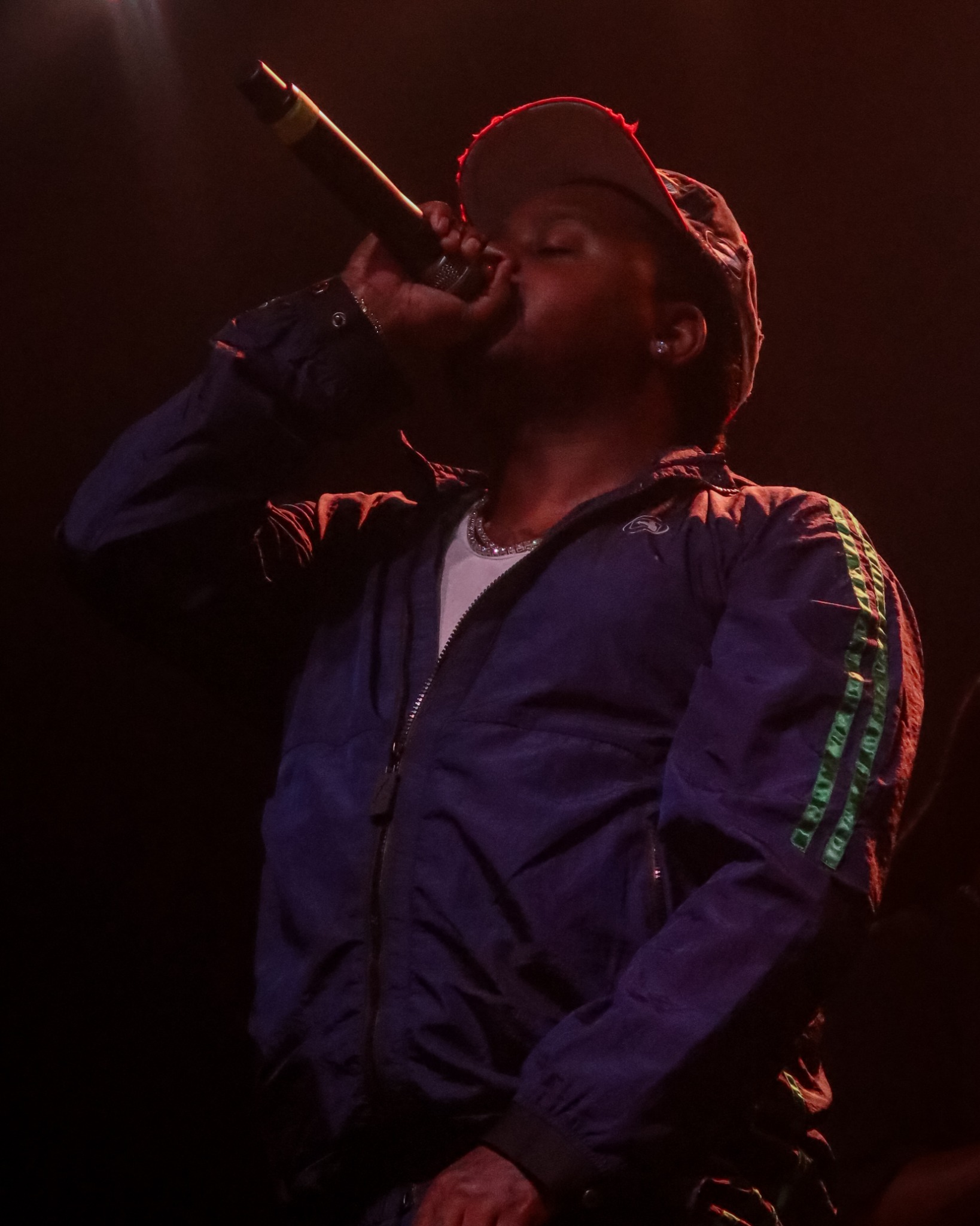 42 Dugg performing into a microphone under warm red stage light