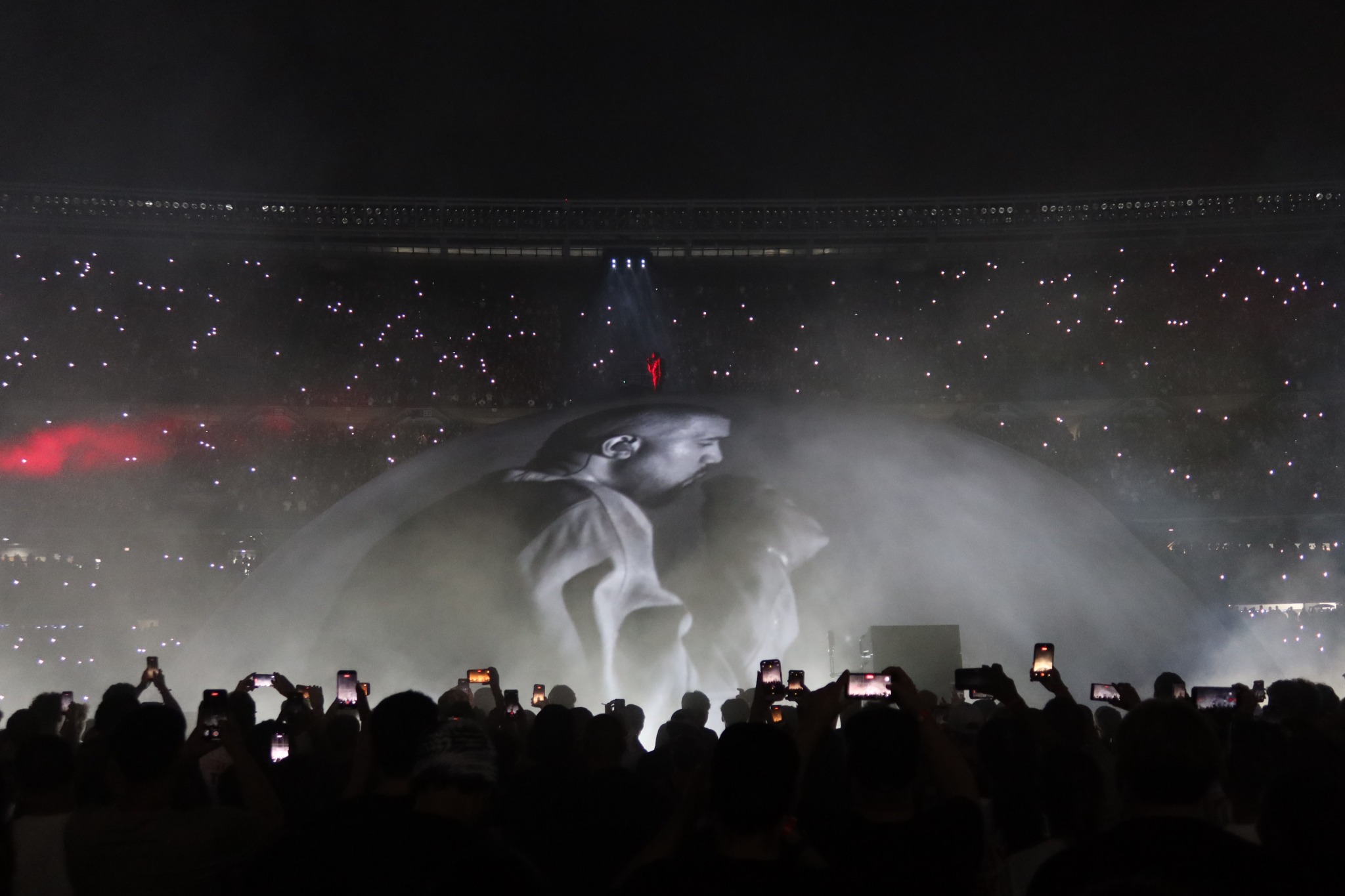 Ye and Ty Dolla $ign performing beneath the Chicago dome with the crowd's lights surrounding the stage